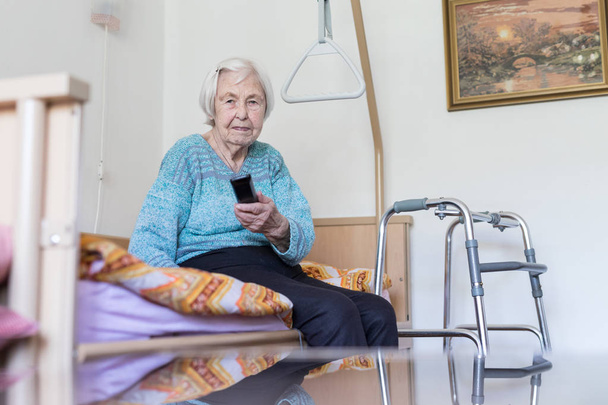 Ηλικιωμένοι 96 χρονών γυναίκα που λειτουργεί τηλεόραση ή DVD με τηλεχειρισμό - Φωτογραφία, εικόνα