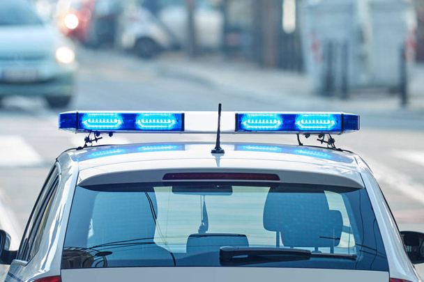 Police car with blue lights on the crime scene in traffic / urba - 写真・画像