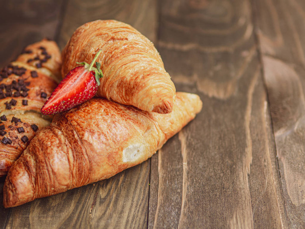 French breakfast. Closeup croissants with strawberry on a wooden planks background - Photo, Image