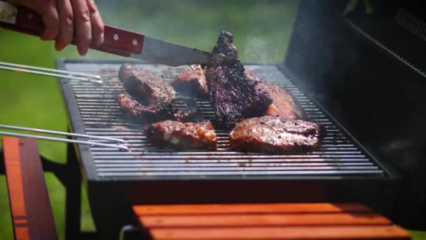 Man flipping barbecued ribs on coal grill in his garden - Footage, Video