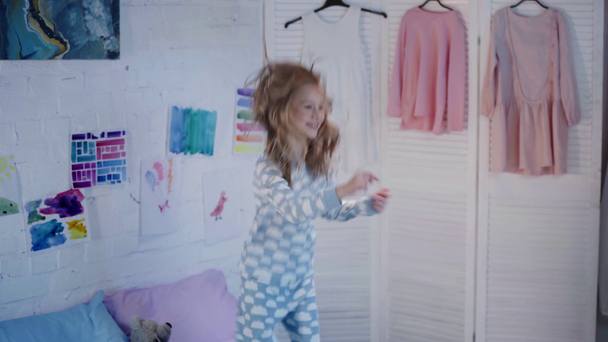 criança pré-adolescente em pijama pulando e acenando as mãos no quarto
 - Filmagem, Vídeo