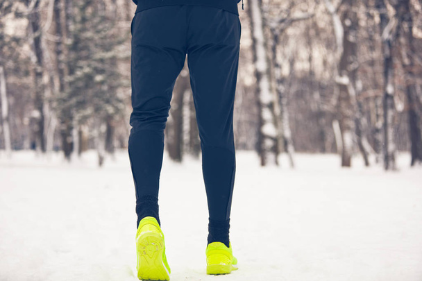 Detalle de las piernas del hombre corriendo en el parque en el momento nevado
. - Foto, Imagen