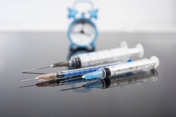 Tempo di vaccinazione. Vaccino in flaconcino con siringa sullo sfondo dell'orologio. Malattia da immunizzazione preventiva
. - Foto, immagini
