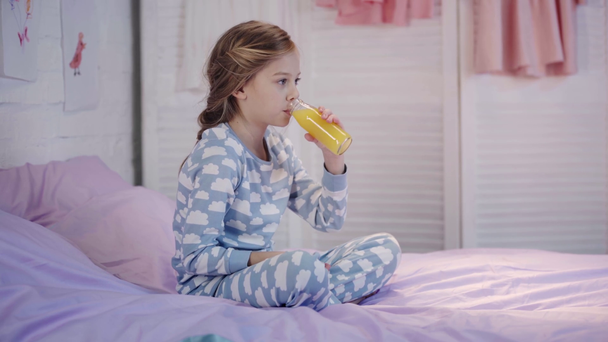 niño en pijama abriendo botella, bebiendo jugo de naranja, mirando a la cámara y mostrando el pulgar hacia arriba con sonrisa en el dormitorio
 - Metraje, vídeo