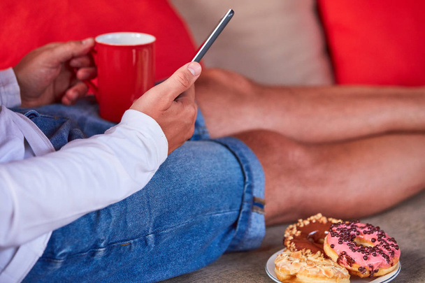 Hombre sentado en un sofá terraza y beber café / té, comer hacer
 - Foto, Imagen