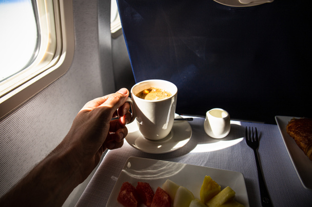 gedeeltelijke weergave van de mens met kopje koffie en eten in het vliegtuig, Rome, Italië - Foto, afbeelding