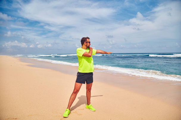 Deportista estirándose en una exótica playa tropical después de correr /
  - Foto, imagen