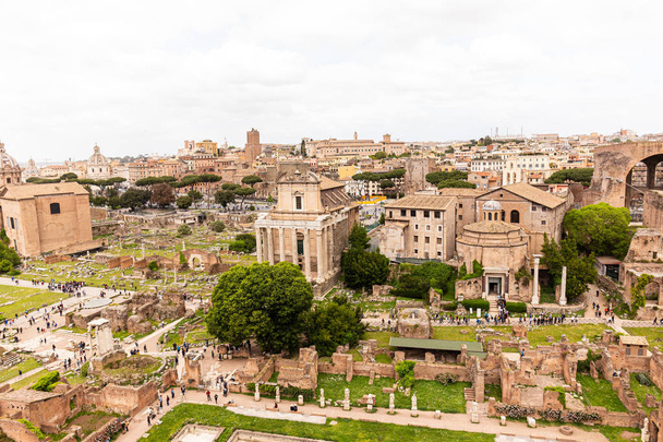 ROME, ITALY - JUNE 28, 2019: tourists walking around roman forum under grey sky - Zdjęcie, obraz