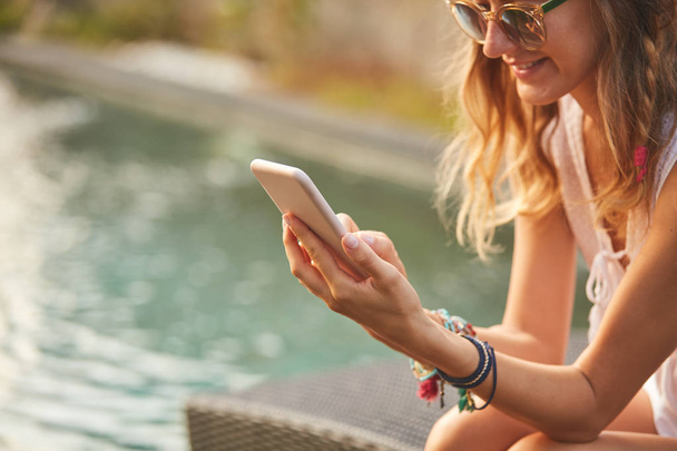 Meisje met behulp van mobiele telefoon liggend op een zwembad dek Lounge  - Foto, afbeelding