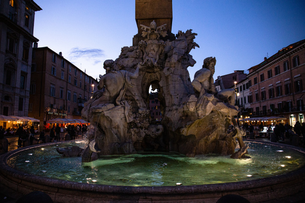 ROME, ITALY - JUNE 28, 2019: crowd of people near fountain with sculptures in evening - Φωτογραφία, εικόνα