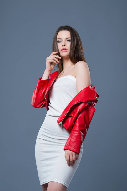 Fashionable style, fashion women's clothing, color combination. Beautiful brunette girl in white dress and red leather jacket isolated gray background - Fotografie, Obrázek