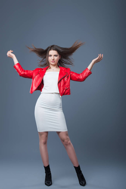 Fashionable style, fashion women's clothing, color combination. Beautiful brunette girl in white dress and red leather jacket. Flying hair - Fotó, kép