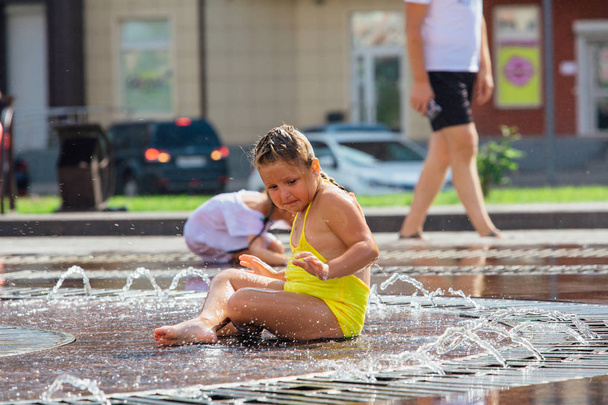 Novokuznetsk, Kemerovo Region, Russia - August 04, 2018: Happy children splashing in a water of a city fountain and enjoying the cool streams of water in a hot day. - Photo, image