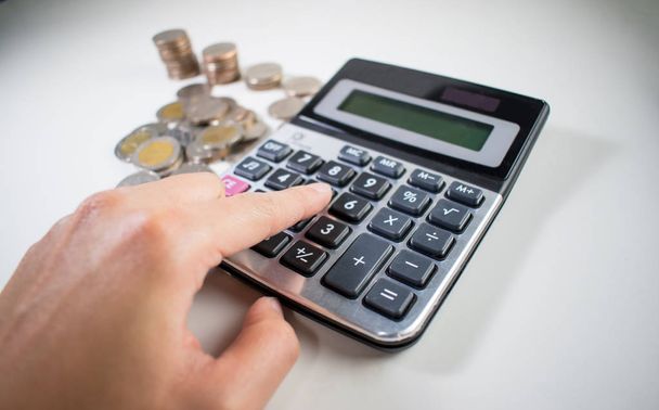 La mano de la mujer está presionando calculadora. Para calcular las monedas. De cerca.
. - Foto, Imagen