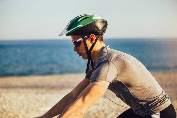 ビーチでマウンテンバイクに乗る男。スポーツとアクティブライフ conce - 写真・画像