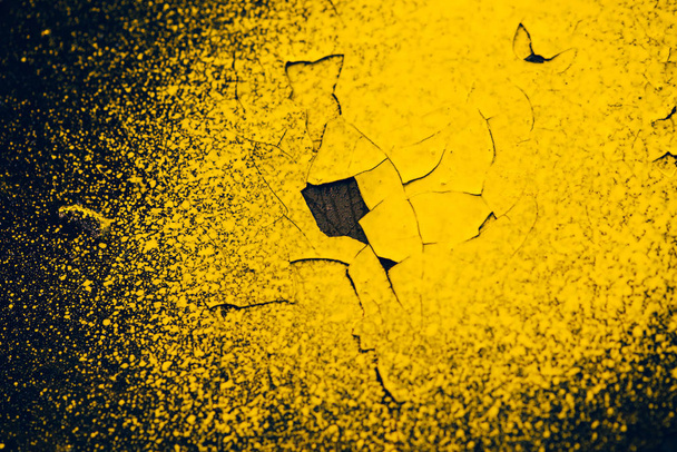 Ruwe donkere zwarte muur met gele sprays van kleurstof. Kleurrijke achtergrond close-up. Donkere zwarte textuur van betonnen wandoppervlak met gele vlekken van verf. Geschilderde achtergrond. Exfoliated Paint. Flaking stucwerk - Foto, afbeelding