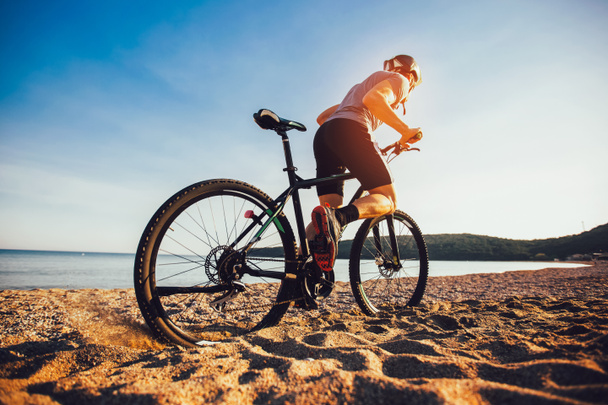 Человек катается на горном велосипеде по пляжу. Спорт и активная жизнь
 - Фото, изображение