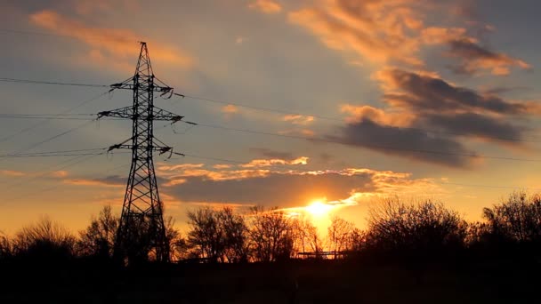 Zeitraffer-Video. Silhouette eines Strommasten mit Bäumen vor dem Hintergrund eines wunderschönen dramatischen Sonnenuntergangs mit orangeroten Farben. Tag wird Nacht. - Filmmaterial, Video