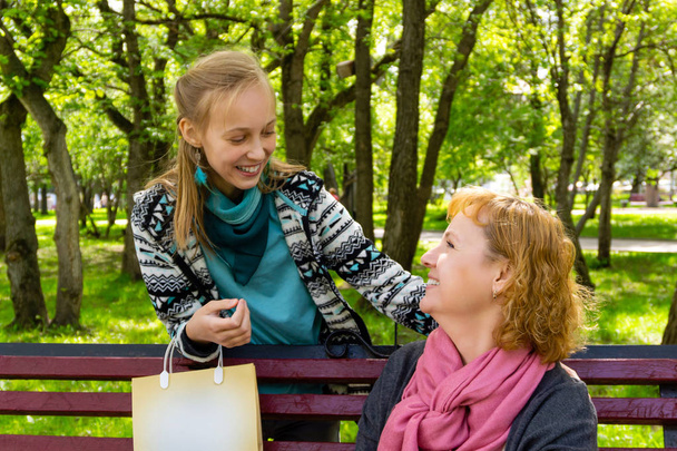 mother and teenage daughter with shopping bag in the park - Photo, Image