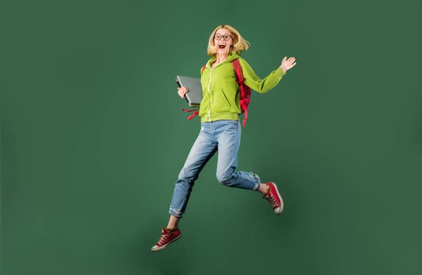 Student. Young funny student in glasses and with book over green chalkboard background. School student. Portrait of a funny blonde female student in university. - 写真・画像
