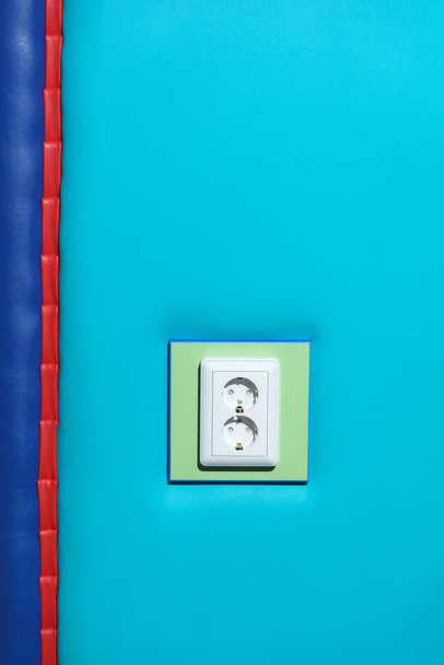 Λευκή πρίζα σε φόντο μπλε τοίχου. Μαλακός τοίχος. Σύνδεση ηλεκτρικού δικτύου. - Φωτογραφία, εικόνα