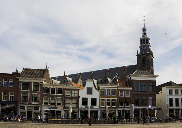 Gouda, Holland, Netherlands, April 23, 2019. The market square in Gouda old town, a street of dutch style facades of houses and view of the bell tower of Sint-Janskerk church (highest in the Netherlands) - Φωτογραφία, εικόνα