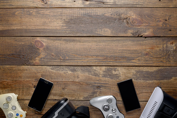 Layout de design para jogos, gamepads, smartphones e óculos VR em fundo de madeira texturizada com espaço de cópia
 - Foto, Imagem