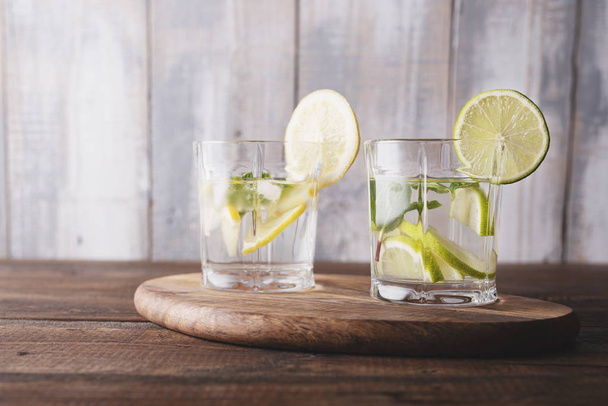 Morning detox. refreshing water with lemon, mint and ice on wooden background - Fotó, kép