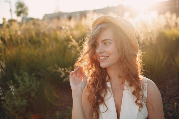 Πορτραίτο της νεαρής θετικής γυναίκας με σγουρά μαλλιά σε ψάθινο καπέλο - Φωτογραφία, εικόνα