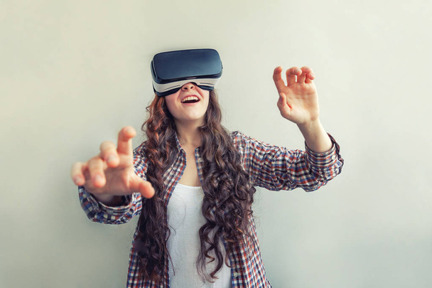 Úsměv mladé ženy při používání virtuální reality brýle na bílém pozadí. Smartphone s použitím brýlí s virtuálními realitou - Fotografie, Obrázek