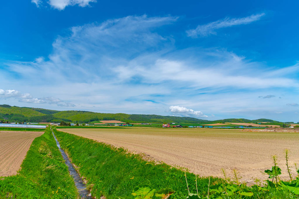 Paisaje rural panorámico con montañas. Gran cielo azul y nubes blancas sobre el campo de cultivo en un hermoso día soleado en primavera
. - Foto, imagen
