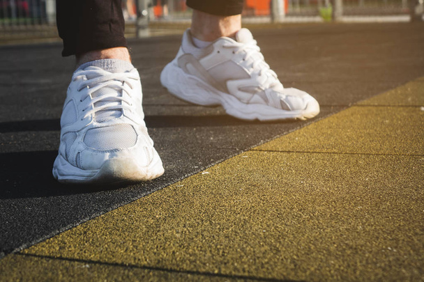 male legs shod in white sneakers on the playground. - Foto, Bild