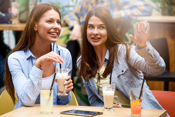 zwei Freundinnen unterhalten sich und amüsieren sich in einem Café - Foto, Bild