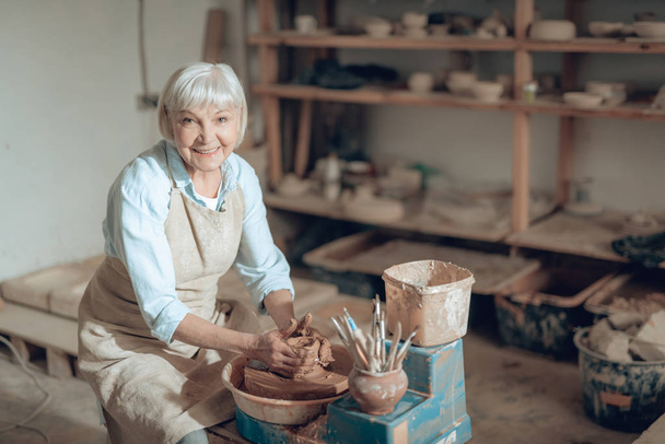Waist up of elderly craftswoman making ceramic bowl in potters studio - Valokuva, kuva