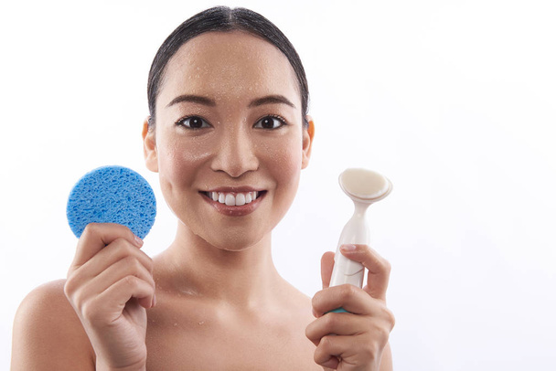 Heureuse femme asiatique démontrant deux éponges cosmétiques
 - Photo, image
