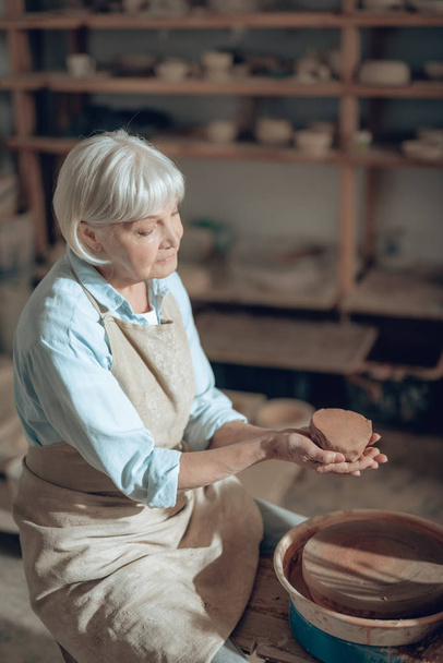High angle of mature craftswoman making clay products in potters studio - Foto, afbeelding