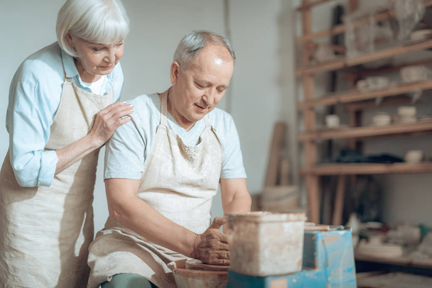 Γηραιότερος ζευγάρι που απολαμβάνει τη δουλειά με βρεγμένο πηλό στο εργαστήρι κεραμικής - Φωτογραφία, εικόνα