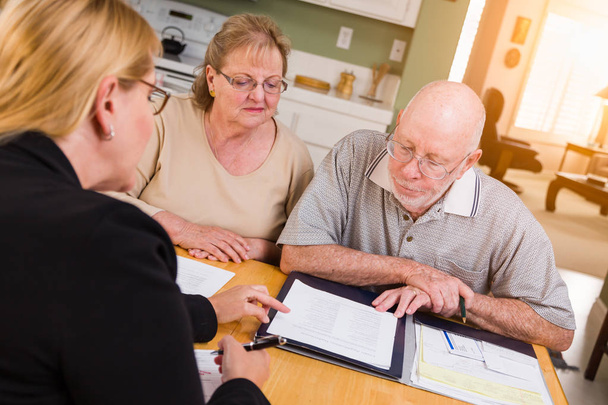 Coppia di adulti anziani esaminando i documenti nella loro casa con l'agente alla firma
. - Foto, immagini