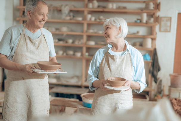 Elderly happy clay masters looking at each other in workshop - Fotografie, Obrázek