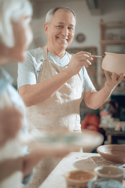 Low angle of happy mature craftsman working in potters studio - Fotoğraf, Görsel
