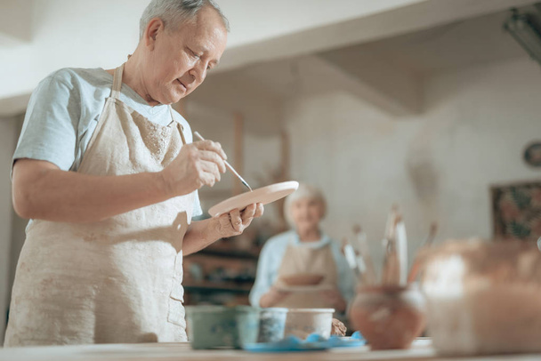 Waist up of elderly craftsman working in potters studio - Foto, imagen