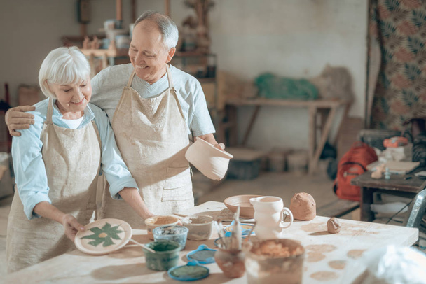 Half length of happy mature potters posing for camera in workshop - Φωτογραφία, εικόνα