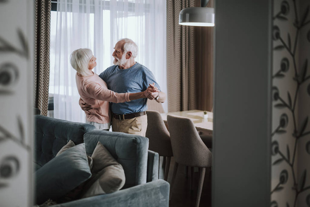 Positive elder couple dancing in living room - 写真・画像