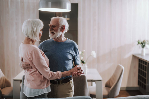 Beloved gray haired couple dancing in living room - Photo, image