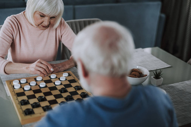 Elder lady thinking on next step playing checks - Фото, изображение