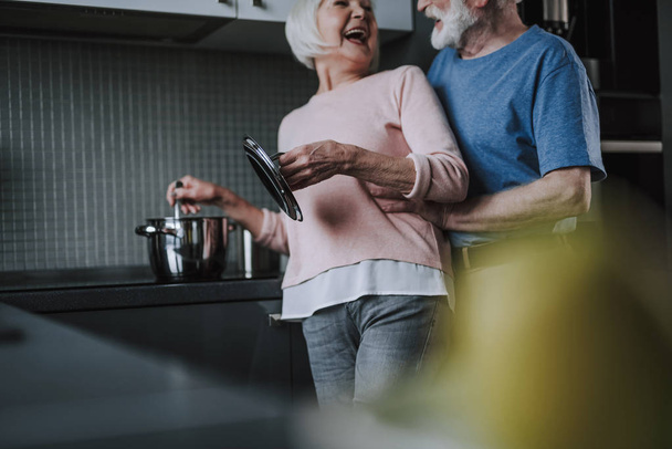 Happy laughing senior couple cooking on kitchen - Photo, Image