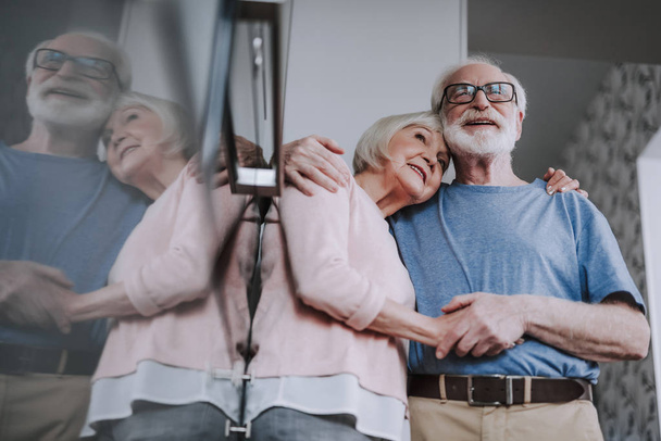 Feliz pareja de ancianos abrazándose juntos en la cocina
 - Foto, Imagen