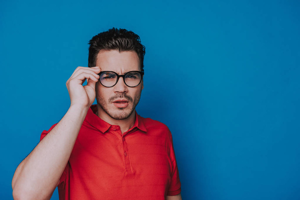 Half length of handsome guy in glasses squinting on blue background - Photo, Image