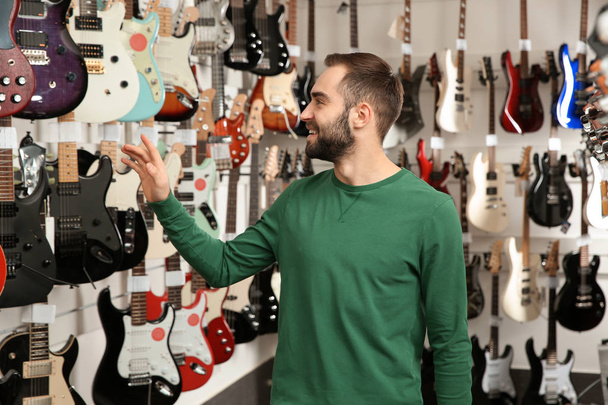 Buyer choosing guitar in modern music store - Foto, Imagen