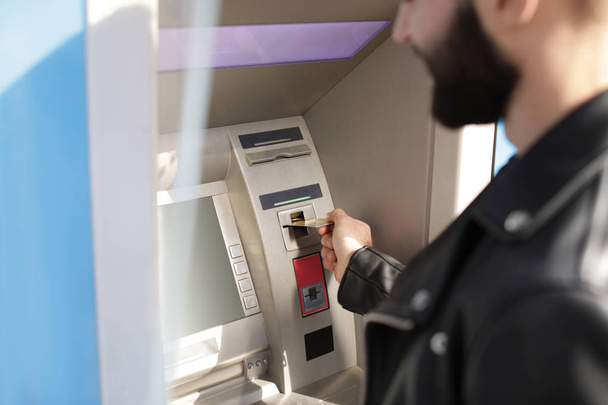 Man inserting credit card into cash machine outdoors, closeup - 写真・画像